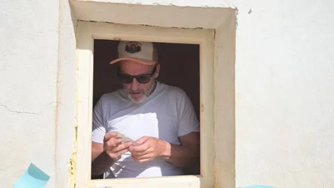 Mature construction worker applying masking tape to a window frame 库存影片 346167886