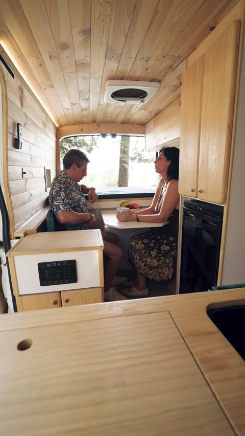 Mature couple enjoying conversation inside a camper van. Vertical Stock Footage 344824433