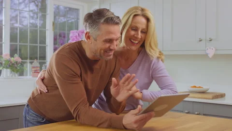 Mature couple at home in kitchen using digital tablet to make video call to Stock Footage 172300218
