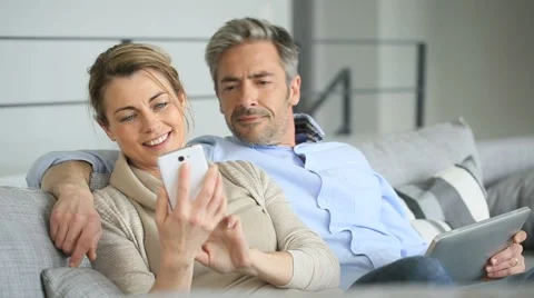 Mature couple at home using tablet and smartphone Stock Footage 48752476