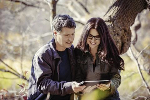 A mature couple looking at a tablet while enjoying a warm fall day in a city par 스톡 사진