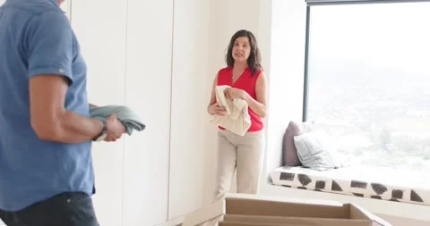 Mature couple noticing donation box on bed, woman in red blouse folding while Stock Footage 341736635