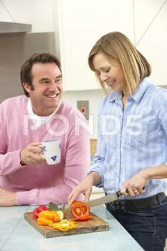 Mature couple preparing meal in domestic kitchen Stock Photos