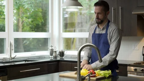 Mature couple preparing vegetables in kitchen, drinking red wine and toasting. 動画素材 88162902