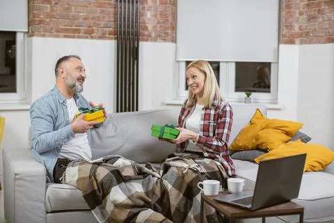 Mature couple sharing with presents while sitting on sofa Stock Photos