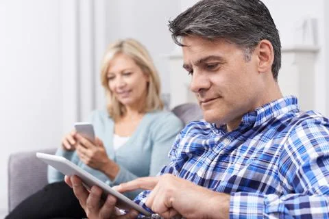 Mature Couple Using Digital Devices At Home Stock Photos