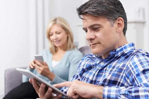 Mature Couple Using Digital Devices At Home Stock Photos