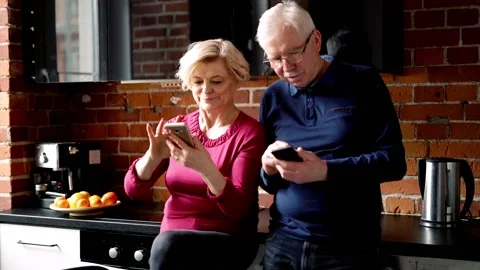 Mature couple using smartphone standing in the kitchen Stock Footage 91185805