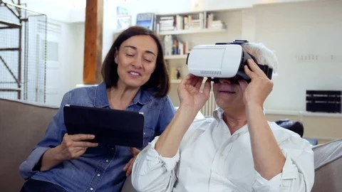 Mature couple using virtual reality headset in living room Stock Footage 81247895