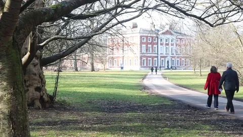 Mature couple walk down path towards stately home Stock Footage 86318907