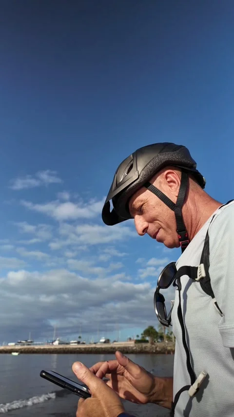 Mature cyclist checking his smartphone on the beach Stock Footage 346561394