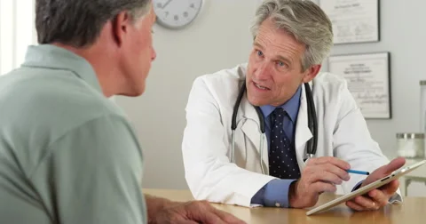 Mature doctor talking with patient and tablet in office Stock Footage