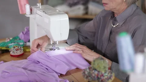 Mature dressmaker sewing close-up on a machine. Womens hands sewing fabric Stock Footage 329395740
