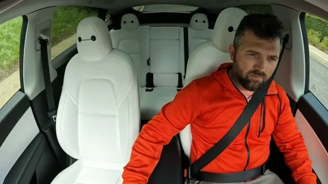 Mature driver drinking water in Tesla Model Y car, driving self drive autopilot Video stock 237300749