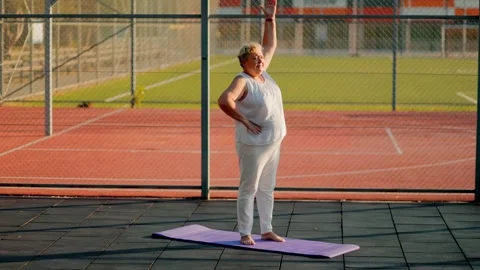 Mature elder person doing shoulder mobility reaches on sports court. fitness and Stock Footage 340994024