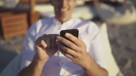 Mature elderly man using smartphone in cafe on the beach Stock Footage 80693022