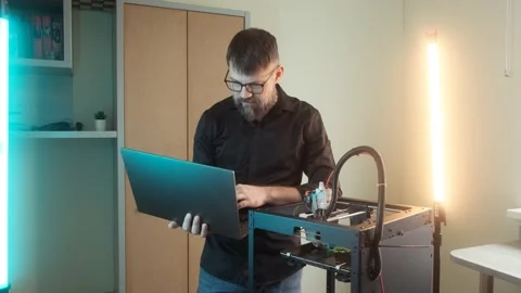 Mature engineer man using a 3D printer at home office workplace Stock Footage 237078503