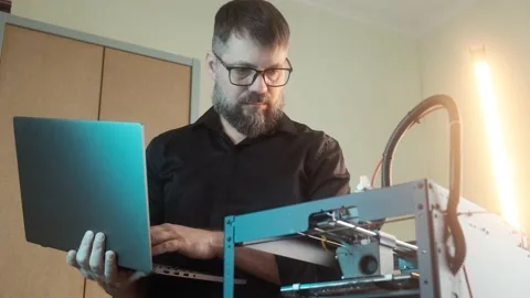 Mature engineer man using a 3D printer at home office workplace Stock Footage 237310335