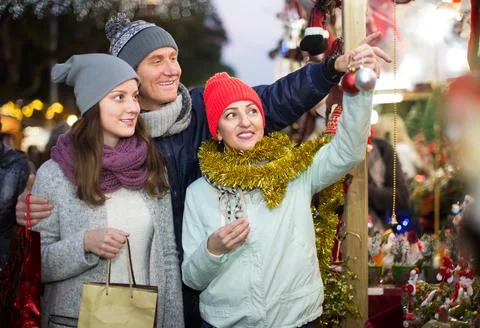 Mature family couple with teen daughter choosing Christmas decoration Stock Photos