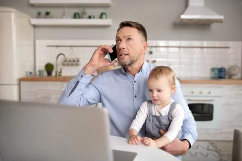 Mature father having a phone call and holding his daughter Stock Photos
