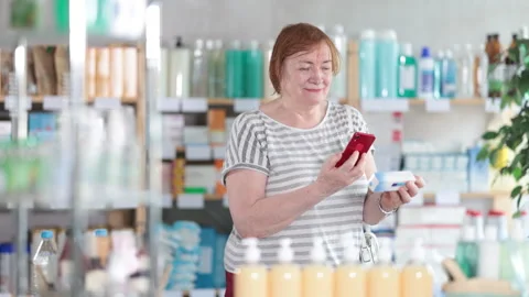 Mature female buyer scans code on package of ointment to check the expiration Stock Footage 310068697