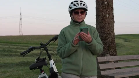 Mature female cyclist checking map on smartphone during evening e-bike ride Stock Footage 335543614