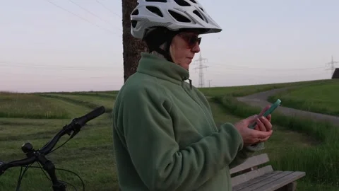 Mature female cyclist checking map on smartphone during evening e-bike ride Stock Footage 335543615