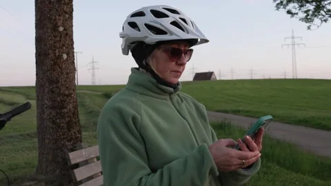 Mature female cyclist checking map on smartphone during evening e-bike ride Stock Footage 335543617