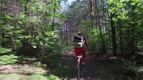 Mature female cyclist on walk in summer forest rides on bicycle with backpack Stock Footage