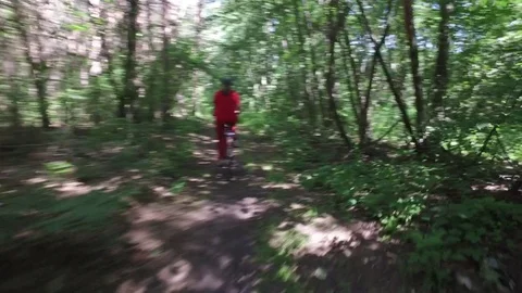Mature female cyclist on walk in summer forest rides on dirt road on bicycle Stock Footage