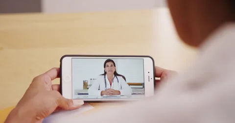 Mature female doctor video chatting on a phone Stock Footage