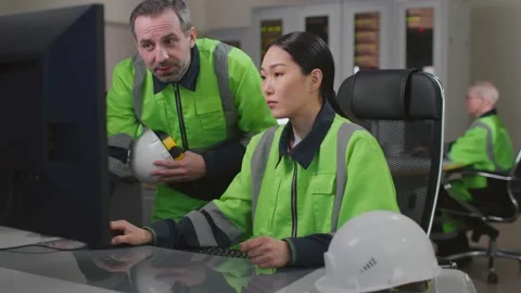 Mature foreman in uniform help young asian woman engineer working on computer Stock Footage 204903035