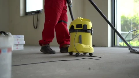 Mature gray-bearded construction worker in overalls vacuums a newly built home Stock Footage 163375526
