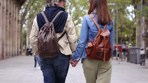 Mature gray haired man walks hand in hand with wife on beautiful city street in Video stock 243227936