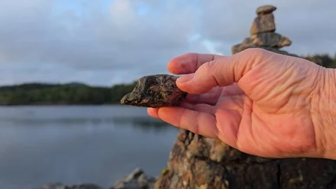 Mature hand examining small natural stones for rock balancing Stock Footage 341895642