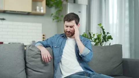 Mature handsome man feels headache while sitting on couch in living room.  Stock Footage 231231906