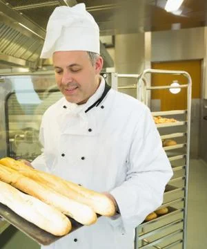 Mature head chef holding some baguettes Stock Photos