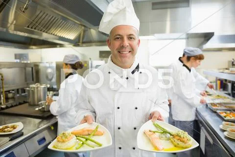 Mature head chef presenting proudly some dinner plates Stock Photos