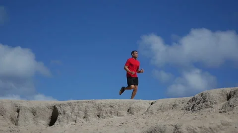 Mature Hispanic male running across a sandy hill 스톡 동영상 59798398