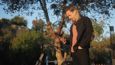 Mature hispanic man using app on smartphone to unlock electric scooter on street Stock Footage 221707912