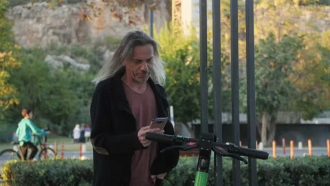 Mature hispanic man using app on smartphone to unlock e-scooter on the street. Stock Footage 222819587