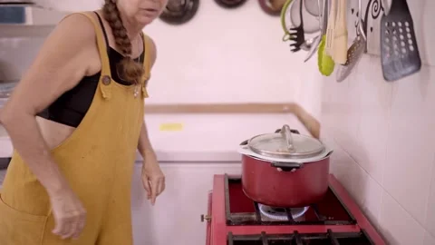 Mature Hispanic woman cooking food in saucepan on stove Stock Footage