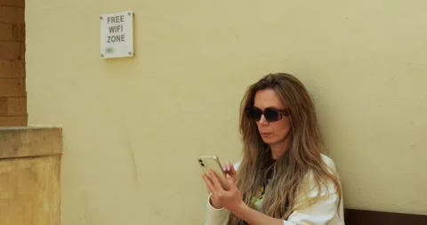Mature lady uses internet technology in public place to search information 스톡 동영상 308877368