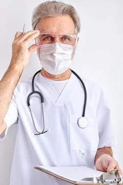 Mature male doctor wearing goggles, face protective mask for protection from Stock Photos