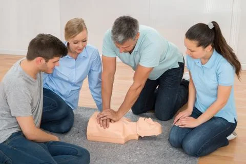 Mature Male Instructor Showing Cpr Training On Dummy To His Student Stock Photos