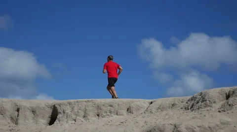 Mature male running across a sandy hill Video stock 59798422