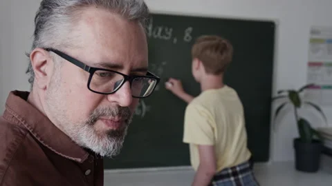 Mature Male Teacher Explaining Math Equation to Teenage Boy at Blackboard Stock Footage 339678191