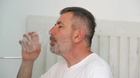 Mature man with a beard drinking water from a glass Video stock 341580631