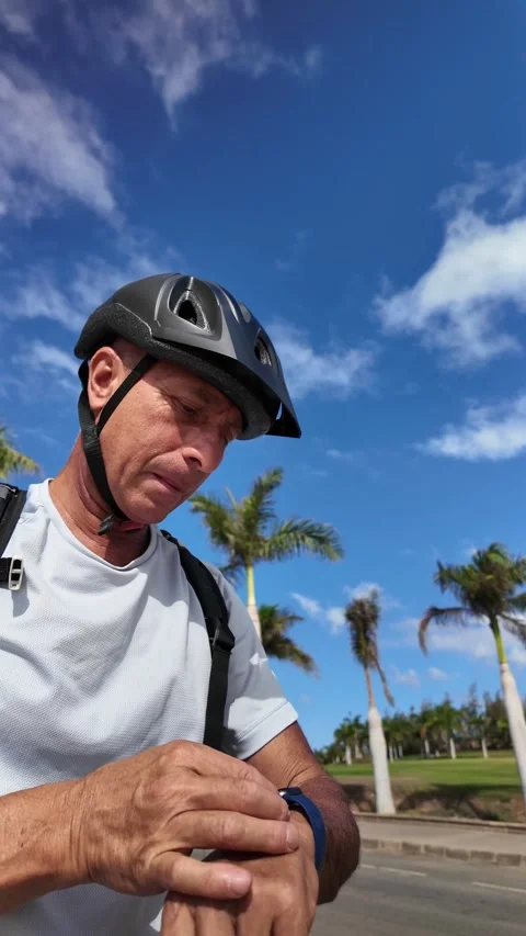 Mature man checking his smartwatch while riding an e-bike Stock Footage 344816317