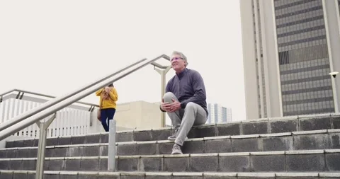 Mature man descending steps pausing while massaging aching knee with cream as Stock Footage 341467384